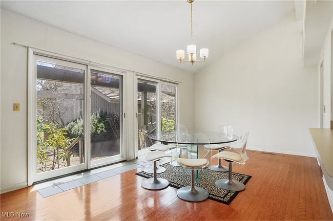 Dining space with lofted ceiling, wood finished floors, visible vents, baseboards, and a chandelier | Image 18