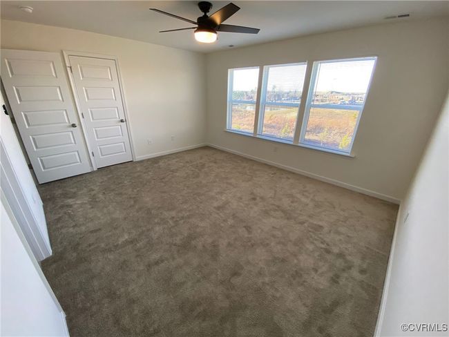 Carpeted spare room featuring ceiling fan, baseboards, and a smoke detector | Image 18