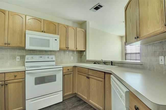 Kitchen featuring sink, white appliances, backsplash, and light brown cabinets | Image 10