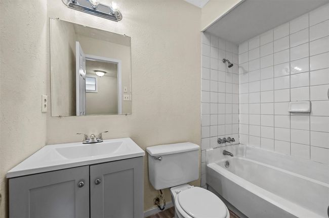 Bathroom with vanity, washtub / shower combination, and a textured wall | Image 12