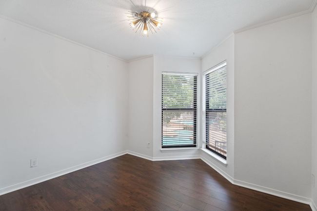 The spacious dining area features a stylish updated light fixture and corner windows with serene pool views. | Image 9