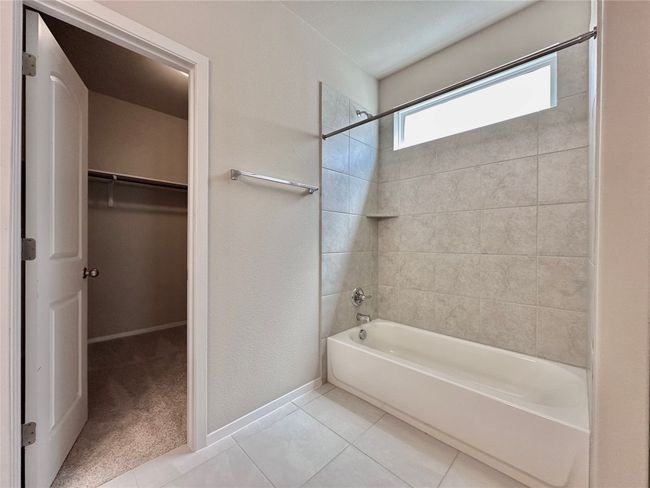 Full bathroom featuring shower / bathtub combination, a walk in closet, and tile patterned floors | Image 14