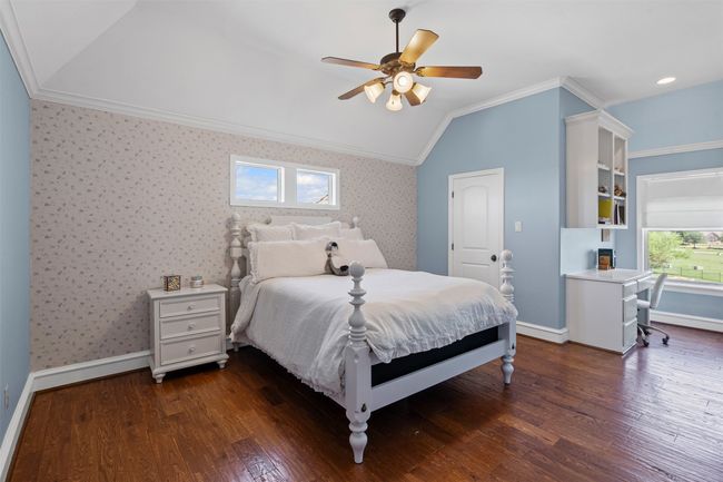 Bedroom with crown molding, dark wood-style flooring, lofted ceiling, wallpapered walls, and baseboards | Image 30