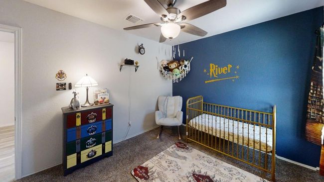 Carpeted bedroom with a crib, a ceiling fan, and baseboards | Image 12