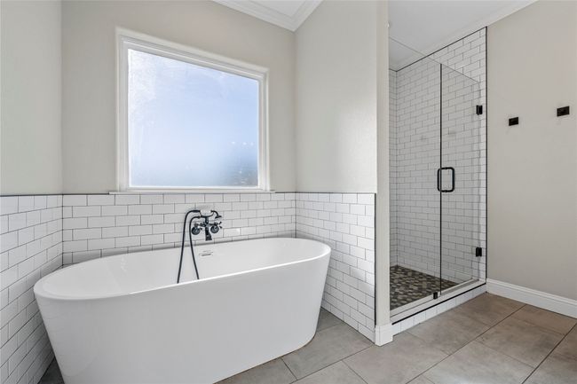Bathroom featuring a freestanding bath, ornamental molding, tile walls, tile patterned flooring, and a stall shower | Image 25