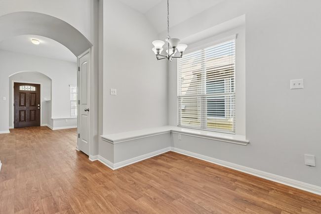 Eat in dining area with light wood-style flooring, arched walkways, and a chandelier | Image 6