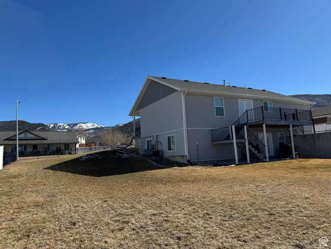 Rear view of property featuring a deck with mountain view, stairs, fence, and a yard | Image 5