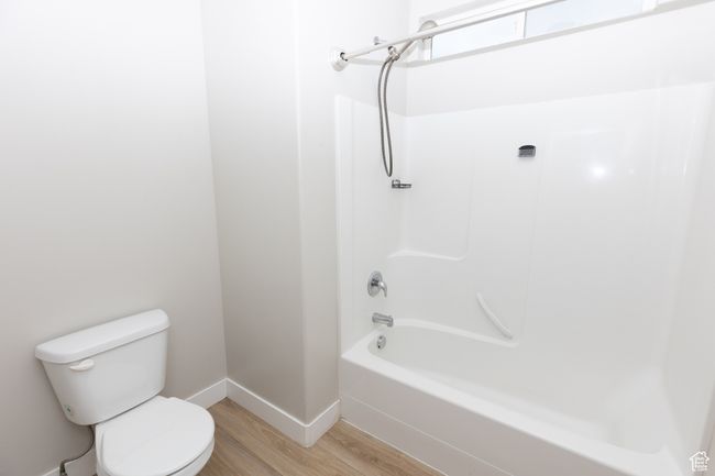 Bathroom with wood finished floors, toilet, baseboards, and shower / bath combination | Image 14