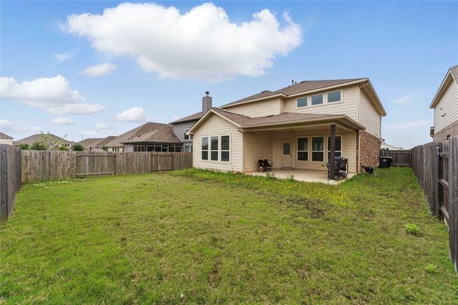 Rear view of property featuring a patio, a yard, a fenced backyard, and a chimney | Image 34