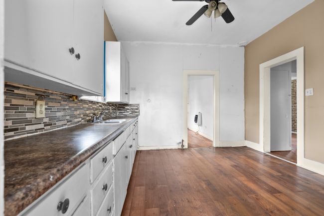 Kitchen featuring a sink, a ceiling fan, decorative backsplash, dark wood-type flooring, and dark countertops | Image 11