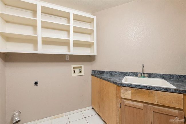 Laundry area featuring hookup for a washing machine, electric dryer hookup, light tile patterned floors, and cabinet space | Image 5
