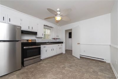 Kitchen featuring appliances with stainless steel finishes, white cabinetry, ceiling fan, and a baseboard heating unit | Image 3