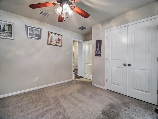 Unfurnished bedroom with carpet flooring, baseboards, a closet, and a ceiling fan | Image 9