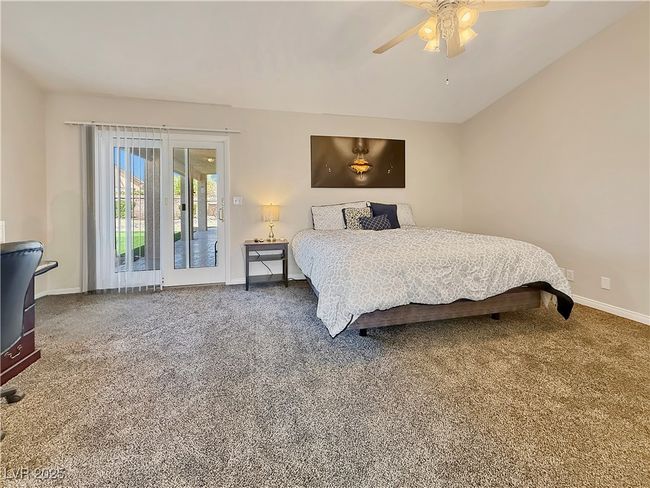 Carpeted bedroom featuring access to exterior, a ceiling fan, baseboards, and vaulted ceiling | Image 23