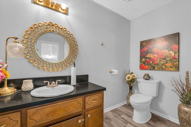 Bathroom featuring vanity, toilet, baseboards, a textured ceiling, and wood finished floors | Image 15
