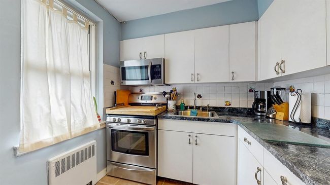Kitchen with appliances with stainless steel finishes, white cabinetry, and tasteful backsplash | Image 11