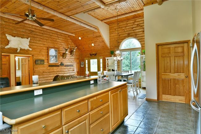 Kitchen with wood ceiling, rustic walls, beamed ceiling, open floor plan, and ceiling fan | Image 15