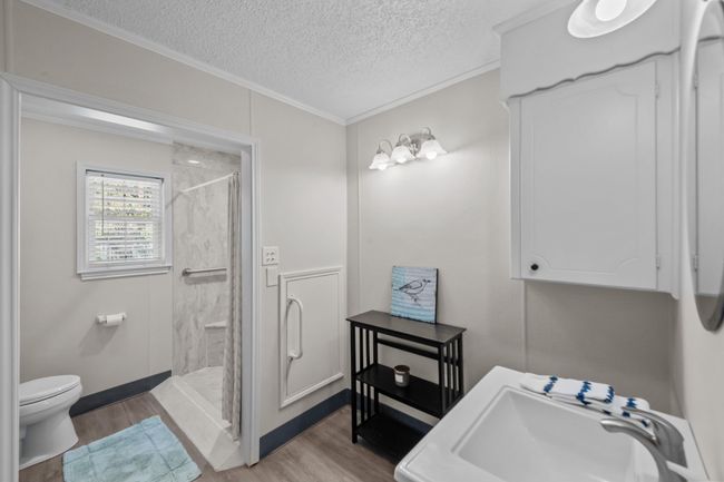 Full bathroom with toilet, a shower stall, a textured ceiling, a sink, and wood finished floors | Image 29