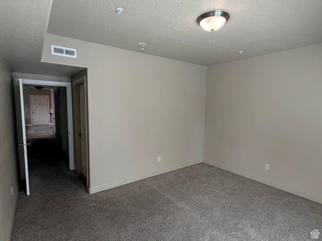 Carpeted spare room with a textured ceiling, baseboards, and a pendent fire sprinkler | Image 12