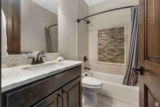 Full bath with tile patterned floors, toilet, vanity, and shower / bath combination with curtain | Image 18