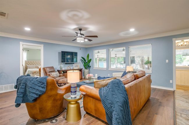 Living room featuring wood finished floors, visible vents, ceiling fan, and crown molding | Image 23