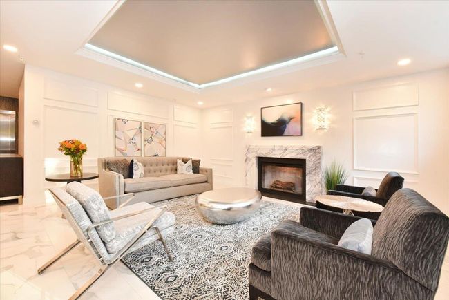 Living room with a raised ceiling, marble finish floors, recessed lighting, a decorative wall, and a fireplace | Image 4