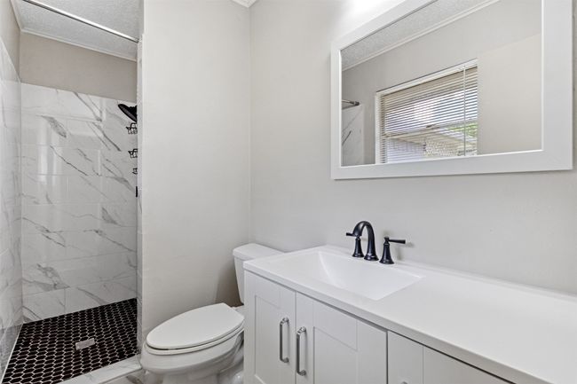 Bathroom featuring vanity, a tile shower, toilet, and marble finish floor | Image 17