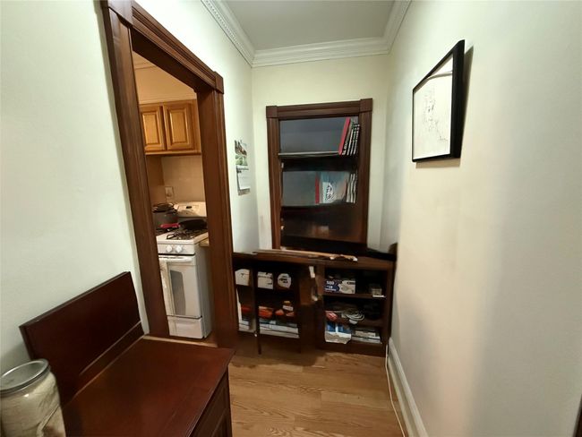 Hallway with light wood-style flooring and crown molding | Image 9