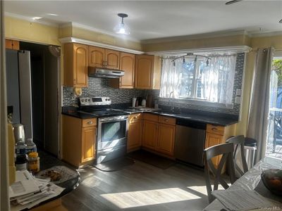 Kitchen featuring decorative backsplash, dark hardwood / wood-style floors, sink, crown molding, and stainless steel appliances | Image 3