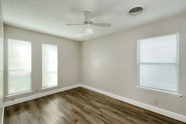 Empty room featuring dark wood-style flooring, plenty of natural light, and ceiling fan | Image 11