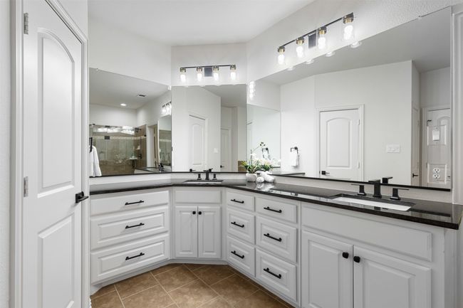 Bathroom with double vanity, a shower stall, tile patterned flooring, and a sink | Image 15
