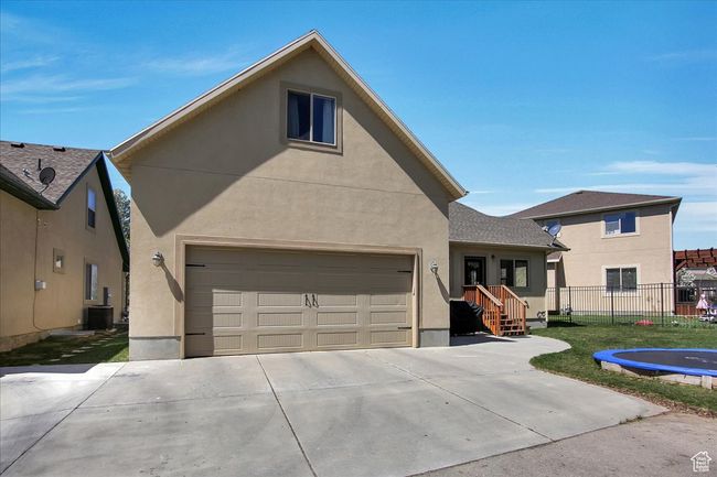 View of front facade featuring stucco siding, concrete driveway, a garage, and fence | Image 26