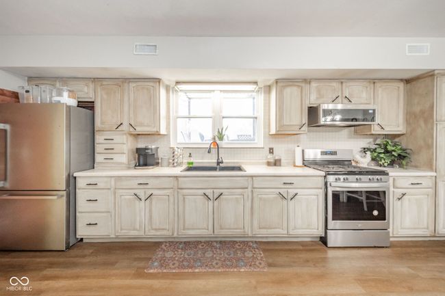 kitchen with light wood finished floors, visible vents, a sink, and appliances with stainless steel finishes | Image 30