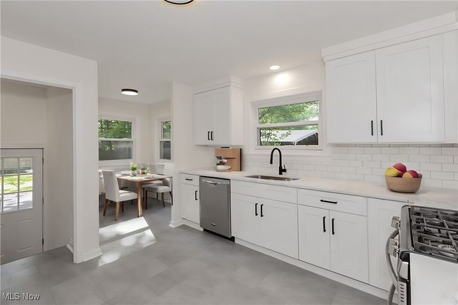 Kitchen with sink, stainless steel dishwasher, gas stove, and light tile patterned floors | Image 15