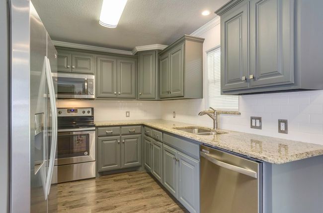 Kitchen with appliances with stainless steel finishes, gray cabinetry, backsplash, a textured ceiling, and crown molding | Image 12