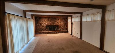 Unfurnished living room with beam ceiling, light tile patterned flooring, and a brick fireplace | Image 3