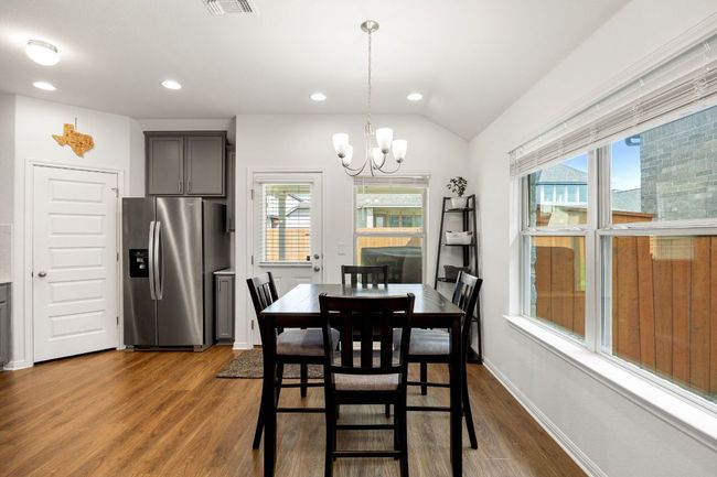 Dining room featuring healthy amount of natural light, wood finished floors, a chandelier, recessed lighting, and vaulted ceiling | Image 12