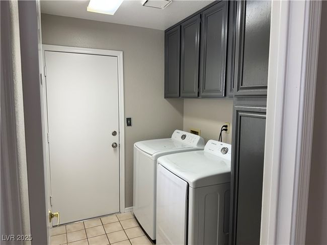Laundry room with washer and clothes dryer, cabinet space, and light tile patterned floors | Image 12