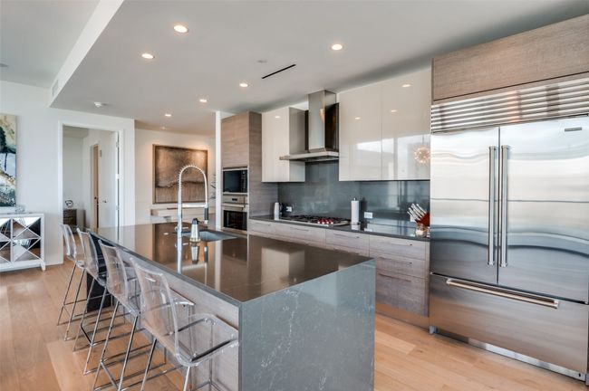 Kitchen featuring modern cabinets, built in appliances, light wood-style flooring, a breakfast bar, and recessed lighting | Image 6
