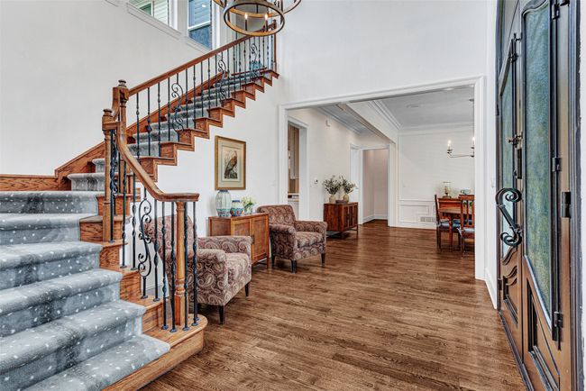 A custom stair runner accents the wood steps on the curved staircase leading to the game room. The foyer is impressive in size, flowing to the dining room on one side and the formal living on the other. | Image 16