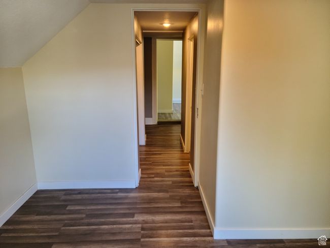 Hall with dark wood-style floors, baseboards, and lofted ceiling | Image 23