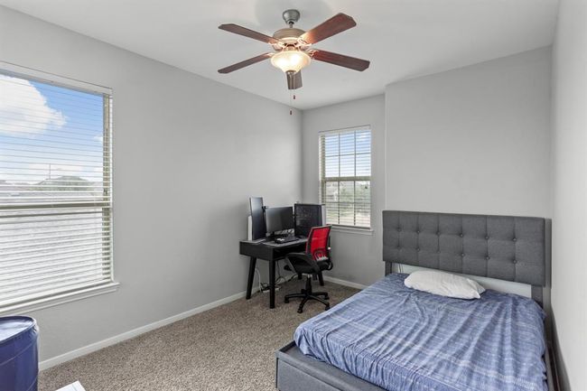 Bright and airy secondary bedroom with neutral paint, plush carpet, a ceiling fan, and windows with privacy blinds. | Image 14