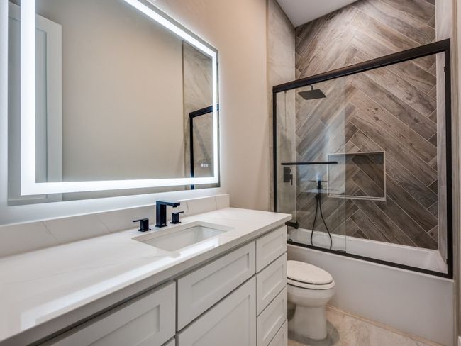 Downstairs guest bath with built in cabinets, Lighted mirror with push button selections for lighting and anti fog, custom herringbone patterned tile surround for shower bath combo. | Image 36