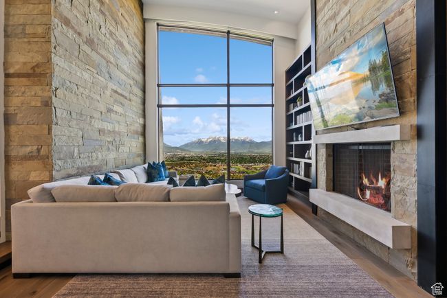 Living area with wood finished floors, a fireplace, and a towering ceiling | Image 16