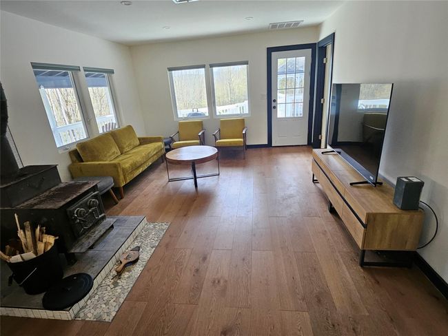 Kitchen with freestanding refrigerator, a sink, stainless steel microwave, black electric stovetop, and light wood finished floors | Image 14