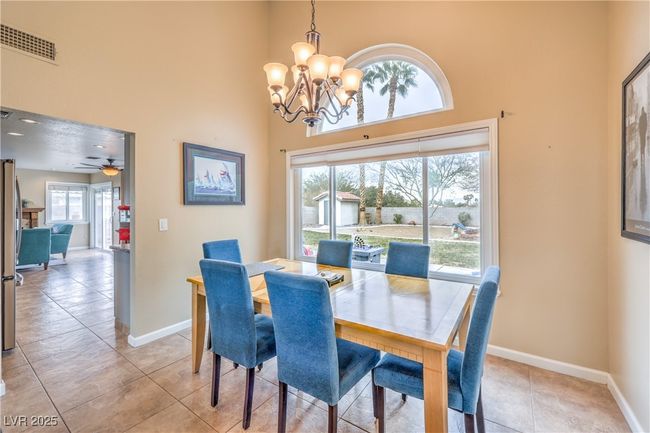 Dining space with a high ceiling, a notable chandelier, baseboards, and large windows | Image 11