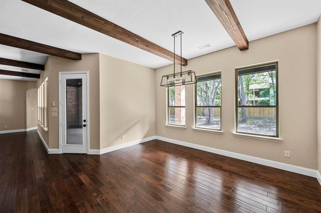Unfurnished dining area featuring beam ceiling, dark wood-style flooring, visible vents, and baseboards | Image 25