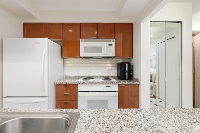 Kitchen featuring white appliances, brown cabinets, and tasteful backsplash | Image 5