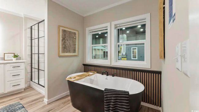 Bathroom featuring wood finished floors, a freestanding tub, a shower stall, and baseboards | Image 23