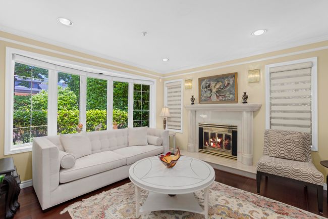 Living area with healthy amount of natural light, wood finished floors, ornamental molding, a fireplace, and recessed lighting | Image 5